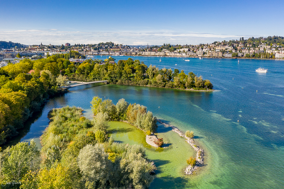 Luftaufnahme Vierwaldstättersee mit grüner Insel, Segelbooten und Luzerner Uferbebauung, herbstliche Lichtstimmung, Zentralschweiz – Jan Geerk Fotograf Basel