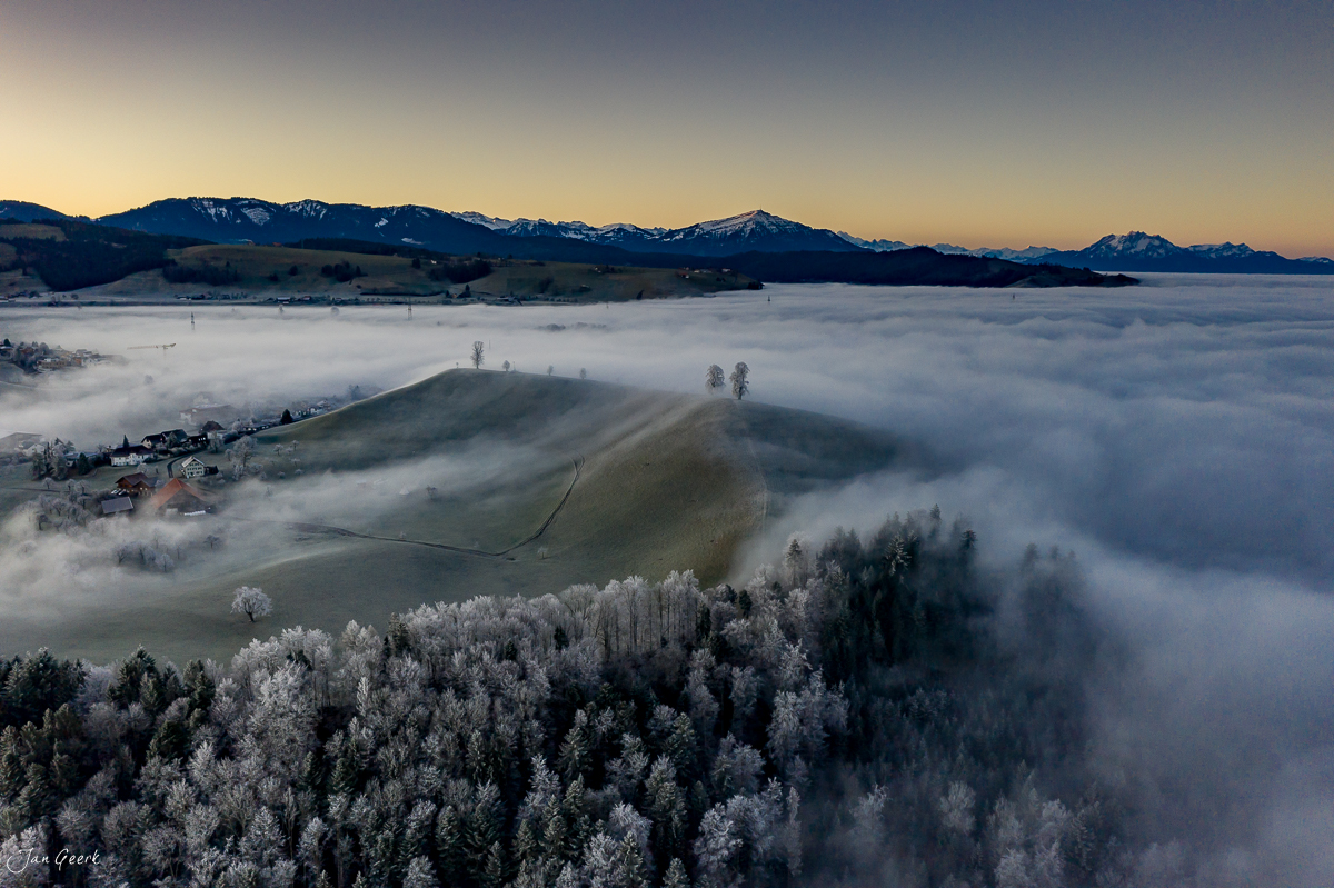 Luftaufnahme von Menzingen mit Nebelmeer, verschneitem Wald und Alpenpanorama im Winterlicht, Zentralschweiz – Jan Geerk Fotograf Basel