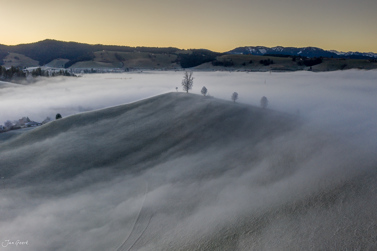 Nebellandschaft mit schneebedecktem Hügel und verschneiten Bergen bei Menzingen in der Zentralschweiz – Jan Geerk Fotograf Basel
