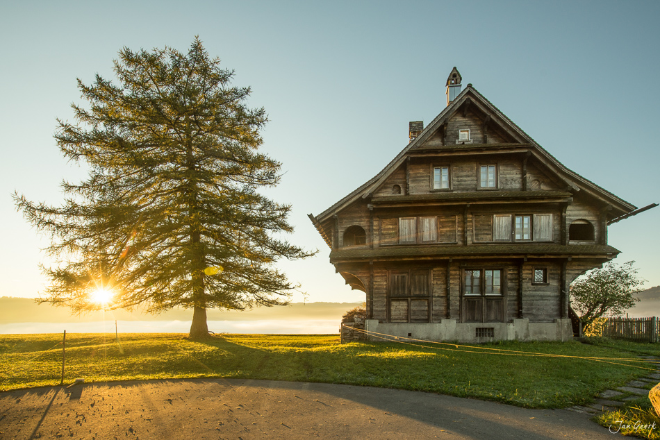 Historisches Holzhaus mit großem Laubbaum bei Sonnenaufgang am Raten, Zentralschweiz Herbst – Jan Geerk Fotograf Basel