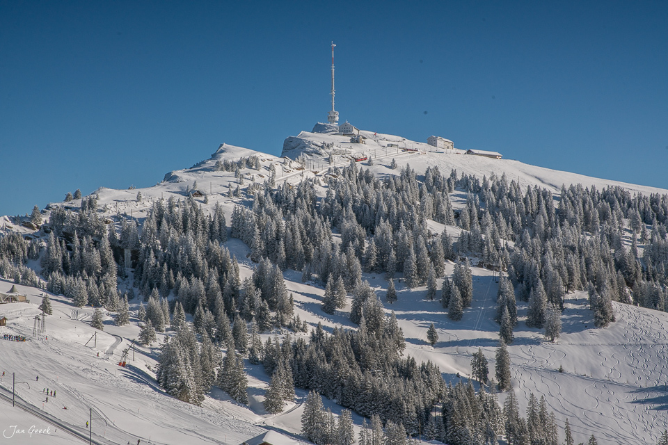 Schneebedeckter Berg mit Sendeturm und Nadelwälder im Winter auf der Rigi Zentralschweiz Schweiz Jan Geerk Fotograf Basel