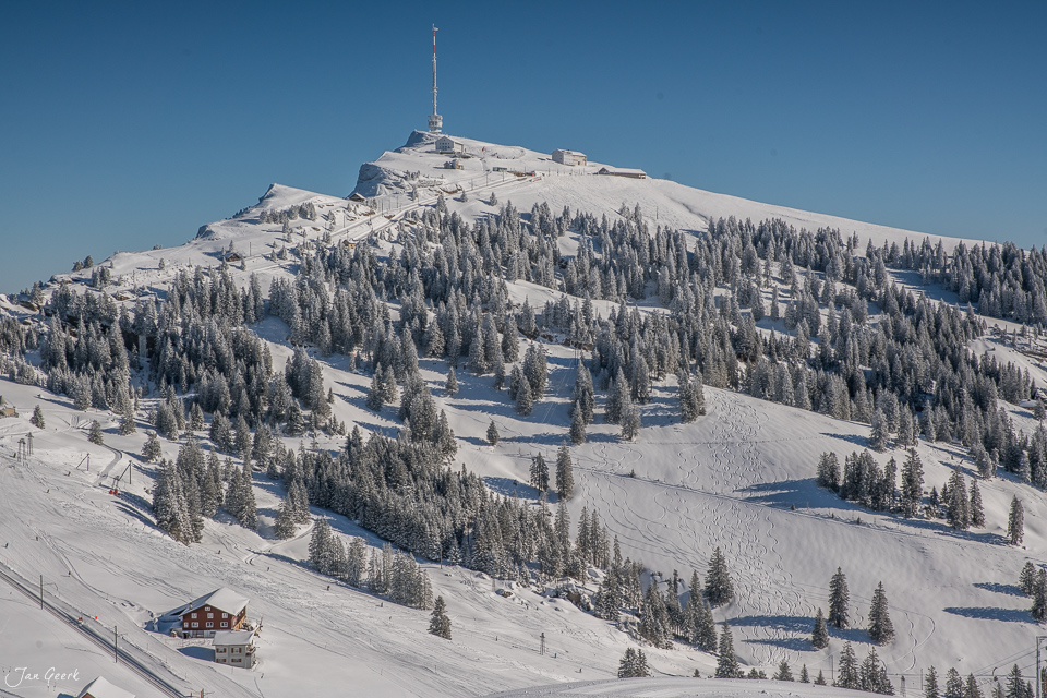 Schneebedeckter Berg mit Bergstation und Nadelwald im Winter auf der Rigi, Zentralschweiz – Jan Geerk Fotograf Basel