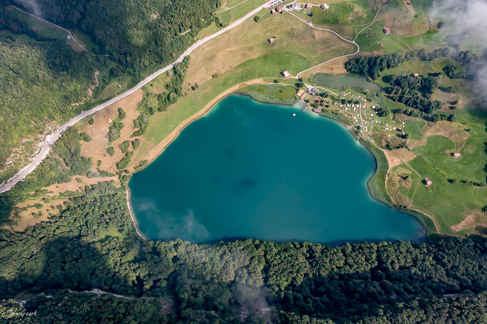 Luftaufnahme des Treib-Sees mit türkisblauem Wasser, umgeben von Wäldern und Wiesen, Sommerlichtstimmung in der Zentralschweiz – Jan Geerk Fotograf Basel
