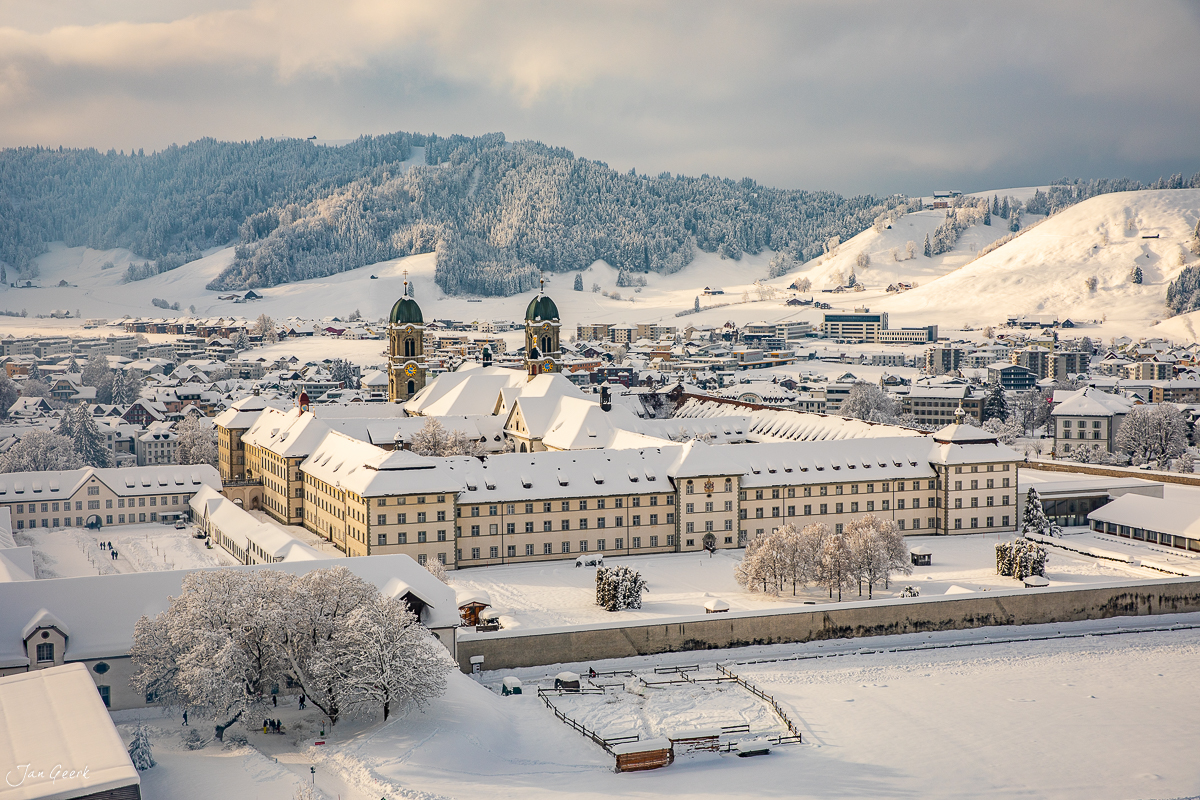 Kloster Einsiedeln im Winter mit verschneitem See, Bergpanorama und Kantlicht – Jan Geerk Fotograf Basel