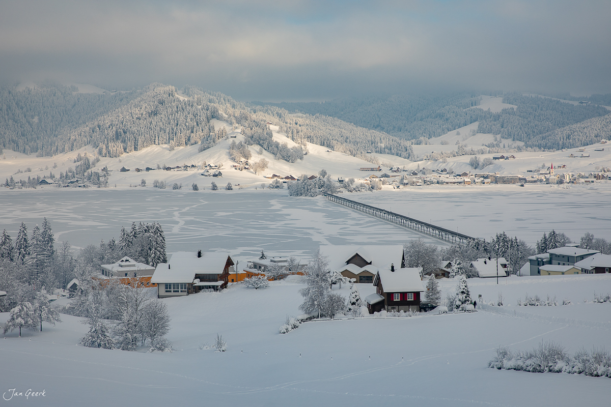 Gefrorener Sihlsee im Winter mit verschneiten Bergen und Dorf Einsiedeln Schweiz Jan Geerk Fotograf Basel