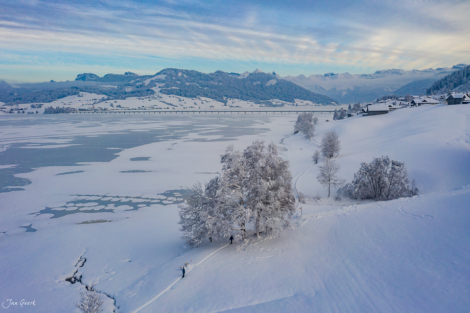 Gefrorener Sihlsee mit verschneiten Bäumen und Bergpanorama im Winter, Luftaufnahme Schweiz – Jan Geerk Fotograf Basel