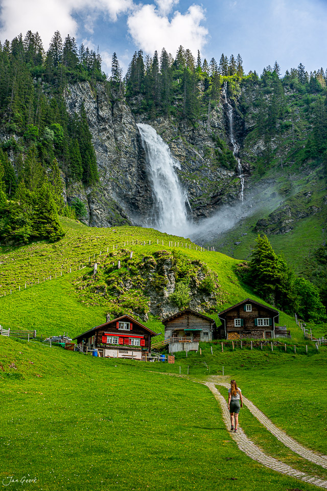 Wanderer auf Alpwiese mit Stäubifall Wasserfall Berghütten Sommer Uri Schweiz Jan Geerk Fotograf Basel