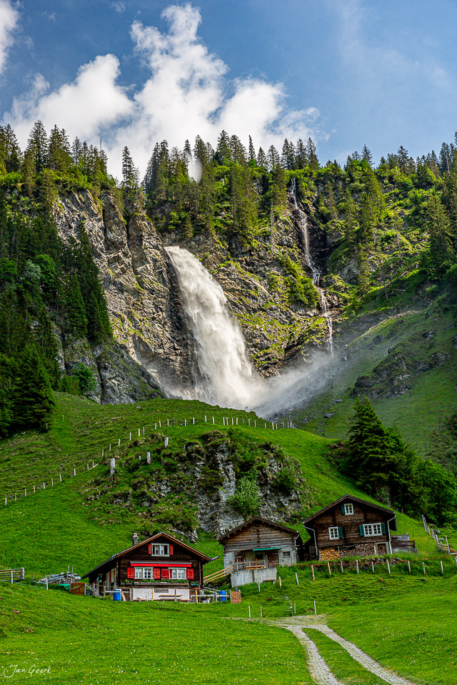 Wasserfall und Alphütten in grüner Berglandschaft Sommer Schweiz Jan Geerk Fotograf Basel