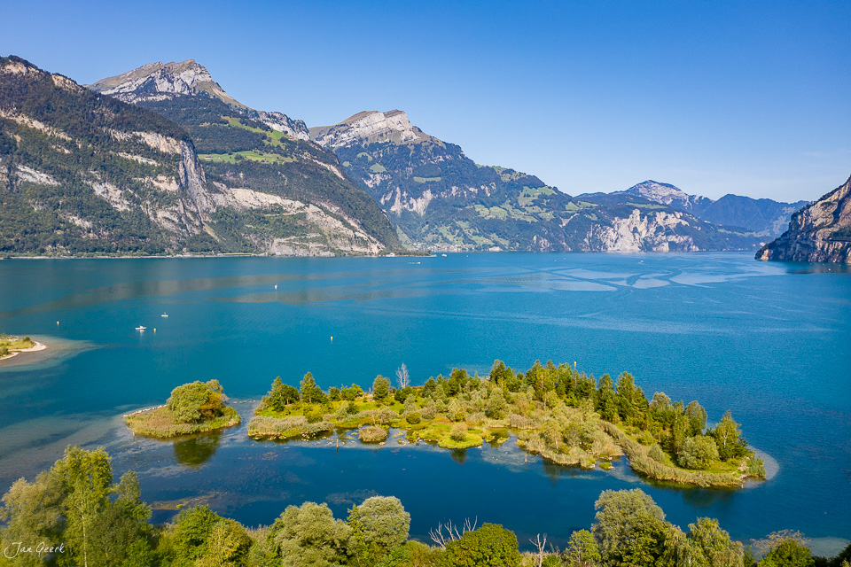 Waldbestandene Insel im türkisblauen Vierwaldstättersee bei Flüelen, Urnerland, Schweiz – Jan Geerk Fotograf Basel