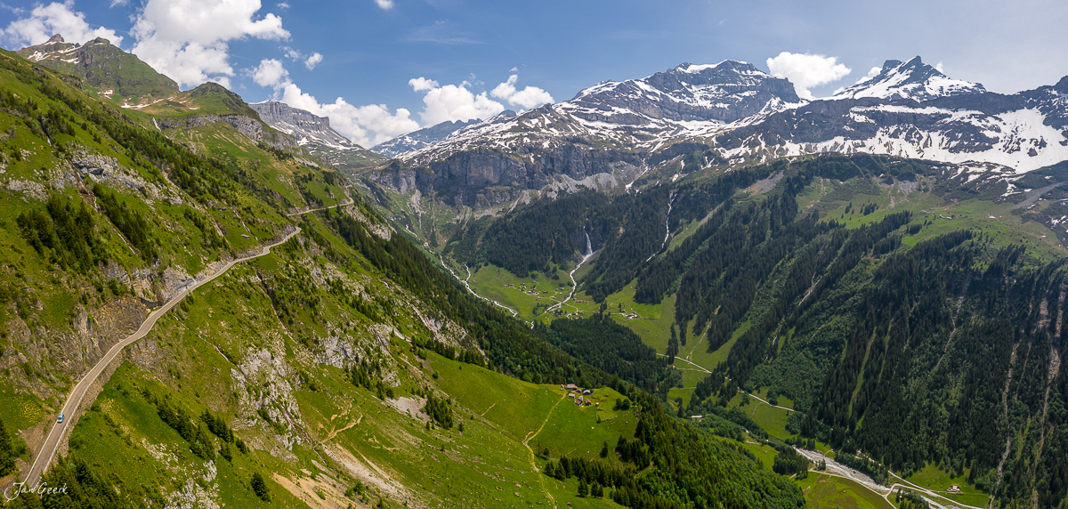 Alpental mit Serpentinen am Klausenpass, grüne Berghänge, Schneefelder, Sommerlicht, Zentralschweiz – Jan Geerk Fotograf Basel