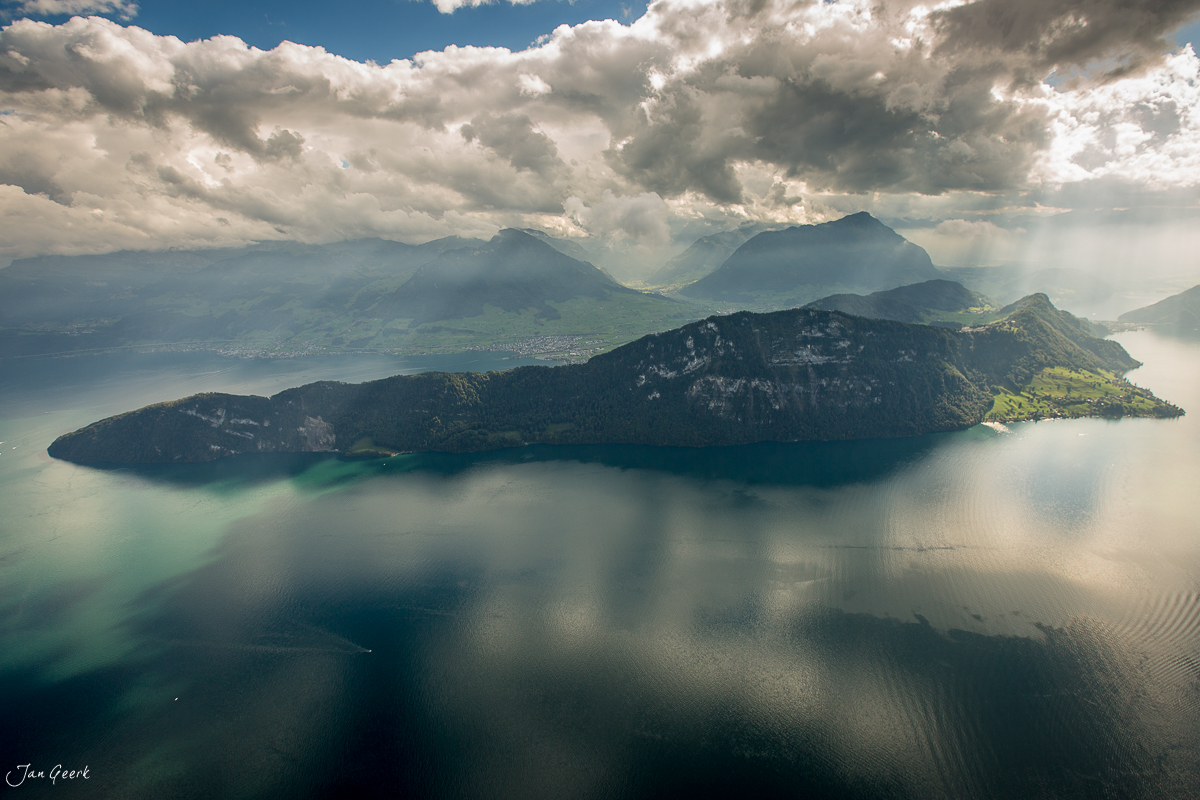 Vierwaldstättersee mit bewaldeter Insel, dramatische Wolkenformation und Alpenpanorama, Zentralschweiz Schweiz – Jan Geerk Fotograf Basel