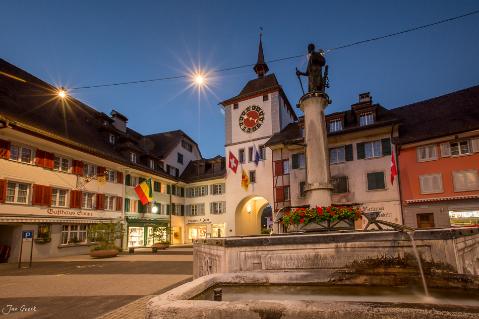 Historische Altstadt von Willisau mit Uhrturm und Statue bei Abenddämmerung in der Luzerner Region Schweiz – Jan Geerk Fotograf Basel