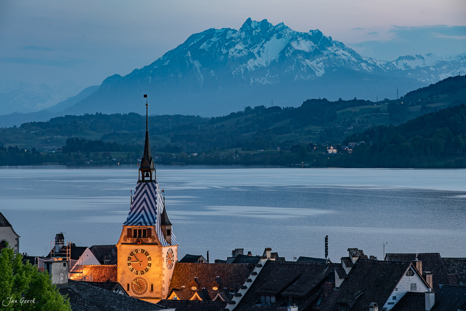 Kirchturm von Zug mit Zugersee und schneebedecktem Pilatus im Hintergrund, goldenes Kantlicht, Zentralschweiz – Jan Geerk Fotograf Basel