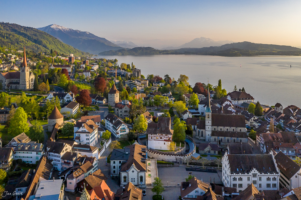 Luftaufnahme der Altstadt Zug am See mit Kirchen und Bergen im Frühling, Zentralschweiz – Jan Geerk Fotograf Basel