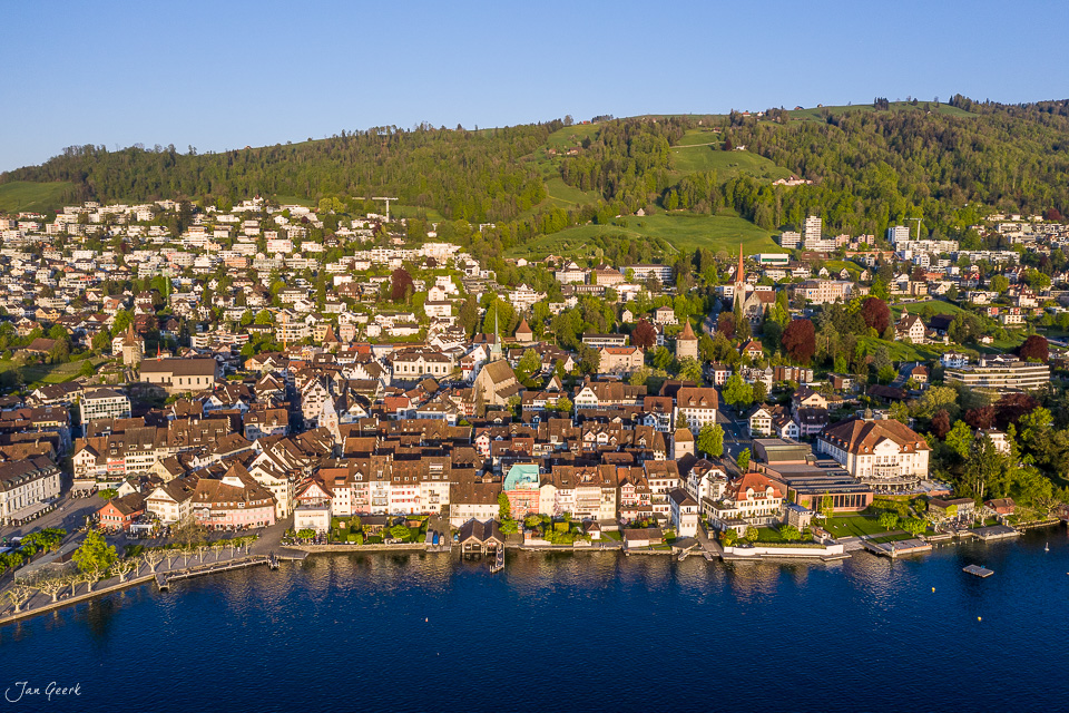 Luftaufnahme von Zug mit See und bewaldeten Bergen im Frühling, Zentralschweiz – Jan Geerk Fotograf Basel