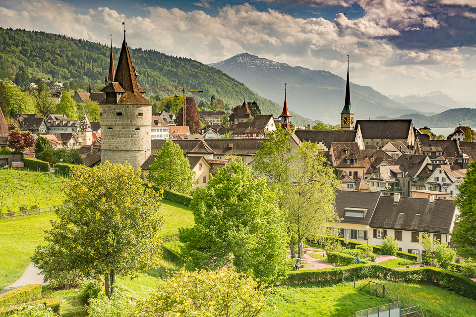 Altstadt Zug mit Türmen und Kirchen im Frühling, grüne Hügel und Berg im Hintergrund, Schweiz – Jan Geerk Fotograf Basel