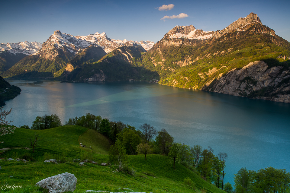 Alpiner See mit schneebedeckten Bergen grüne Wiesen Frühjahrslichtstimmung Zentralschweiz Schweiz Jan Geerk Fotograf Basel