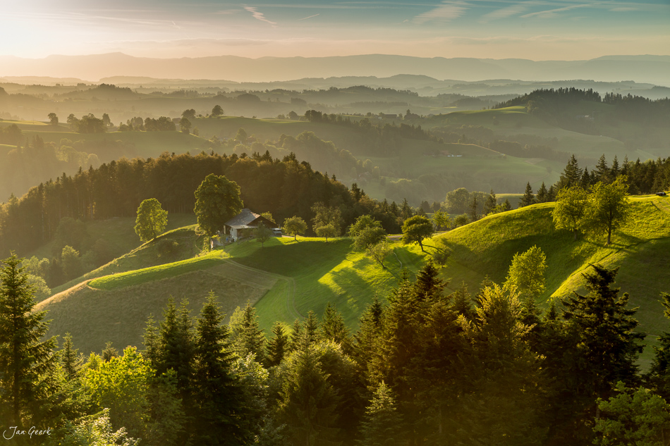 Grüne Hügellandschaft Napf mit Berghof und Wald bei golden-grünem Morgenlicht, Zentralschweiz – Jan Geerk Fotograf Basel