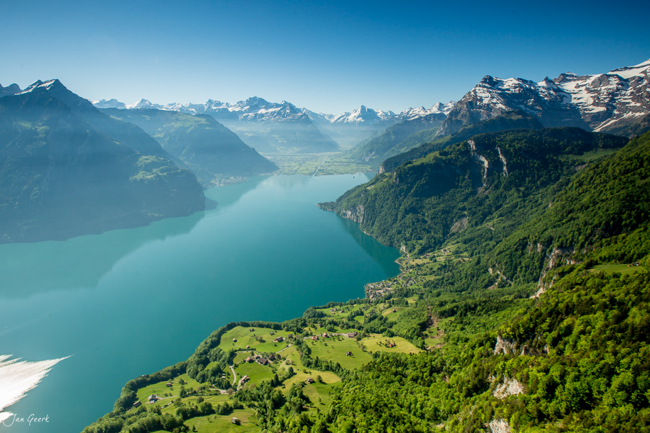 Luftaufnahme des Lauerzersees mit schneebedeckten Alpen, grünen Wäldern und Bergfrühling in der Zentralschweiz – Jan Geerk Fotograf Basel