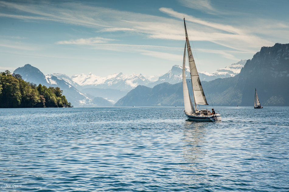 Segelboote auf dem Vierwaldstättersee mit schneebedeckten Bergen im Hintergrund, Frühjahr, Zentralschweiz, Schweiz – Jan Geerk Fotograf Basel