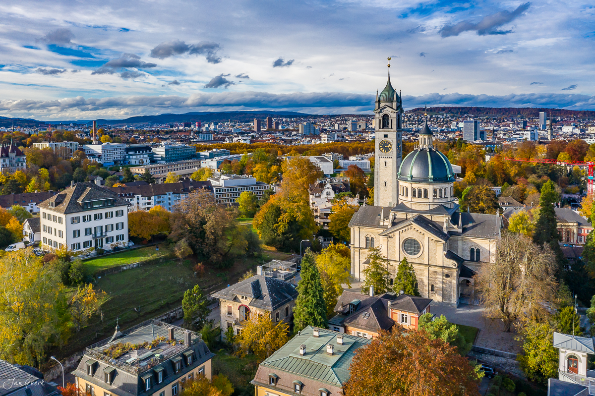 Luftaufnahme der reformierten Kirche Zürich mit Herbstfarben, Alpen und Zürichsee im Hintergrund – Jan Geerk Fotograf Basel