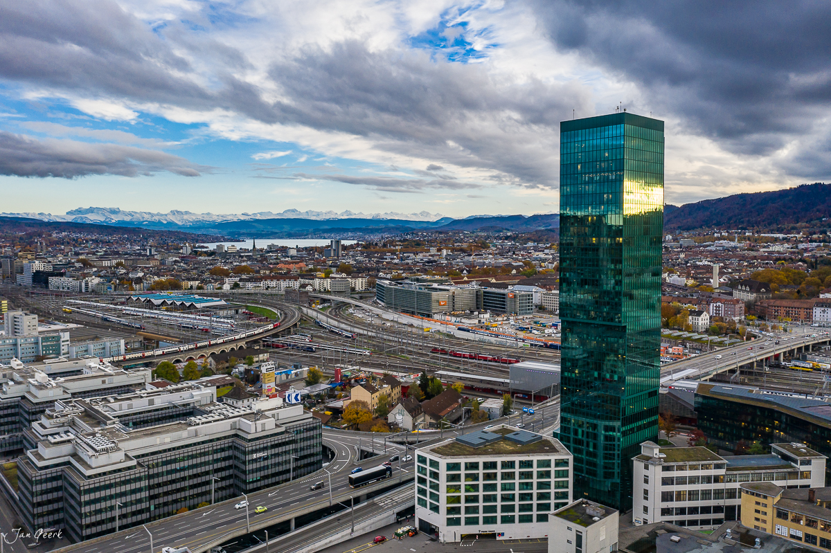 Prime Tower Drohnenaufnahme Zürich mit Hochhaus, Bahnhof und Alpenpanorama im Herbst, Schweiz – Jan Geerk Fotograf Basel