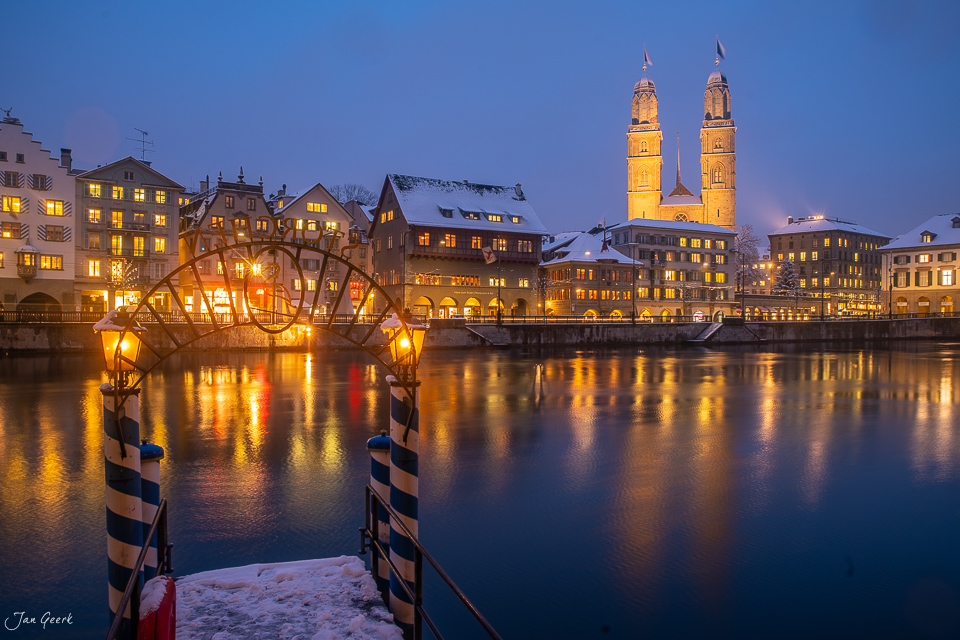 Limmatquai Zürich Winter mit verschneiten Uferhäusern und beleuchteten Kirchtürmen bei Nacht Schweiz Jan Geerk Fotograf Basel