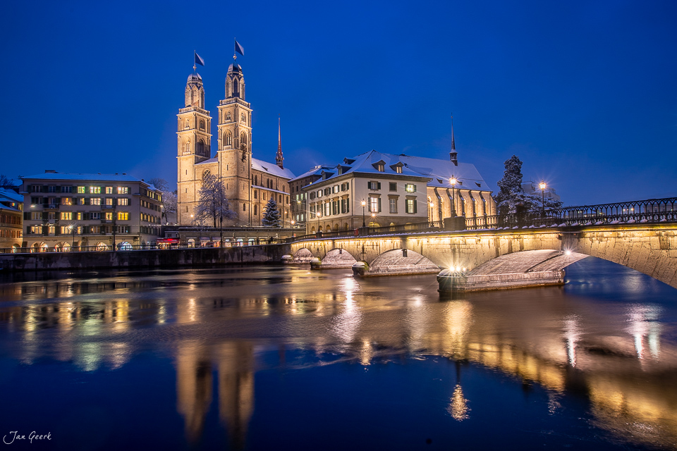 Grossmünster spiegelt sich im verschneiten Fluss während der blauen Stunde in Zürich Schweiz – Jan Geerk Fotograf Basel