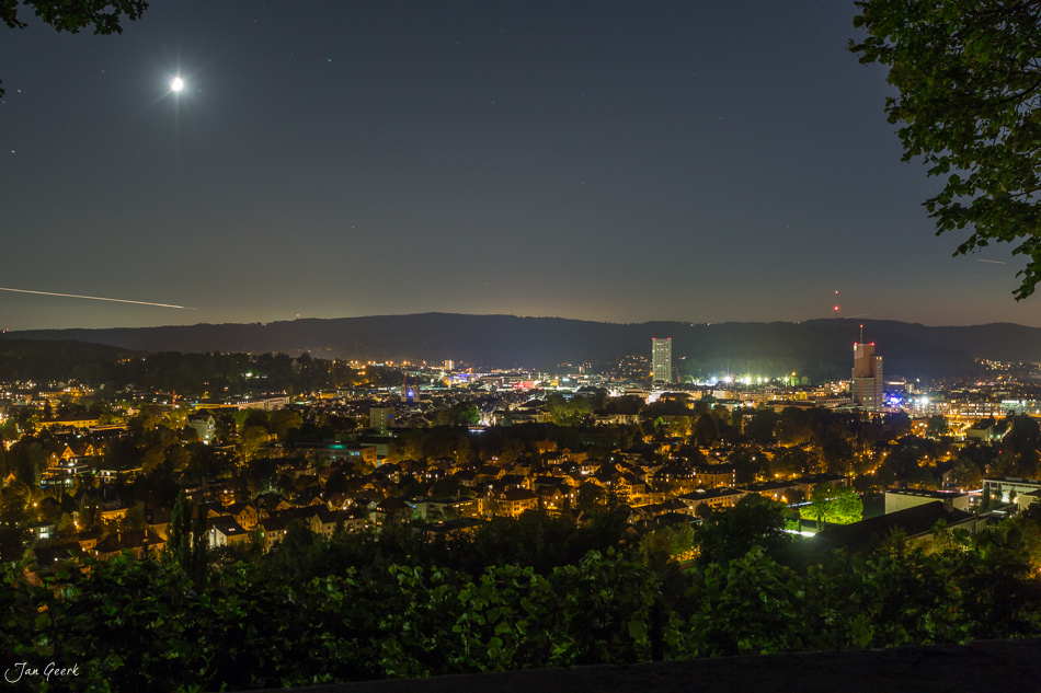 Winterthur Nachtaufnahme mit beleuchteter Innenstadt, Reben im Vordergrund, Mond am Sommerhimmel, Schweiz – Jan Geerk Fotograf Basel